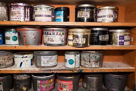 A shelf holding various containers of old paint